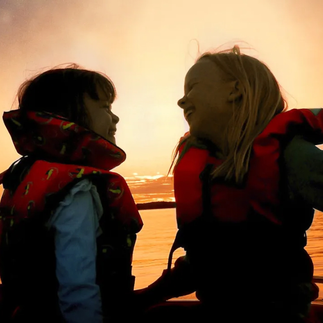 Två flickor i motorbåt i skymning, Mälaren Stockholm.