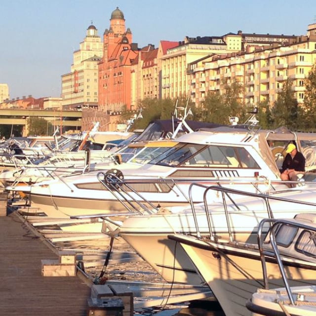Motorbåtar mellan y-bommar Rörstands båtklubb, med St Eriksgatan och Sportpalatset i bakgrunden.