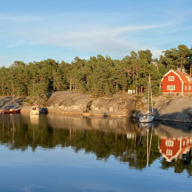 Vacker spegelblank naturhamn i gyllene eftermiddagsljus med båtar i Stockholms Skärgård, Stora Kalholmen.