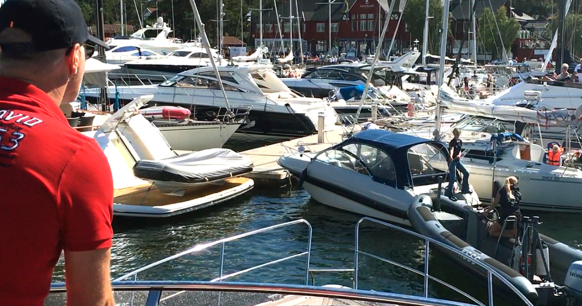Man på flybridge i motorbåt i en stressig hamn, Sandhamns gästhamn vid Seglarhotellet.